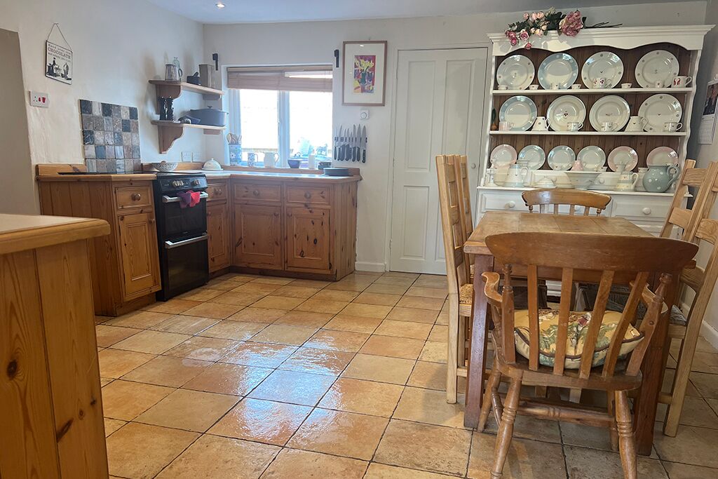 Kitchen and dining area with wooden cupboards, stove, table and chairs