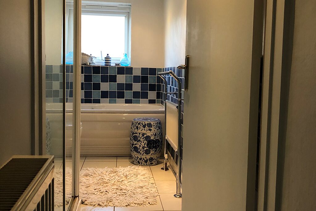 Bathroom with a bathtub, window and blue and white tiles
