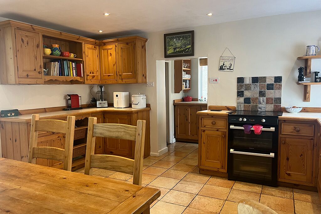 Kitchen with wooden cupboards, dining table, chairs and stove