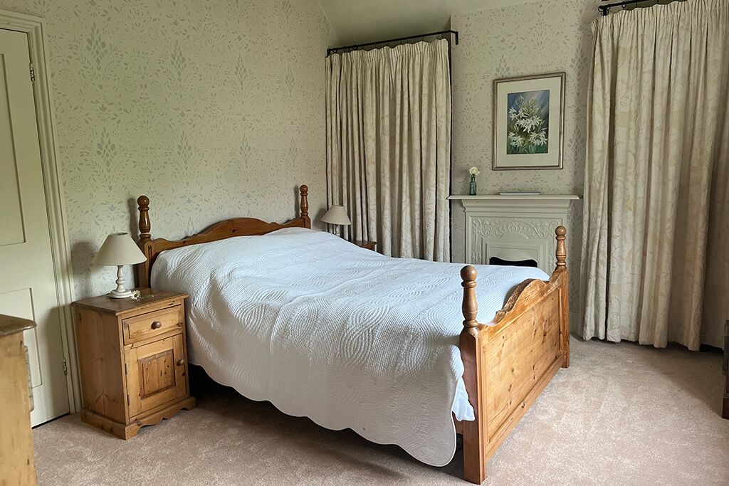 Bedroom with a wooden bed, bedside tables, fireplace and curtains