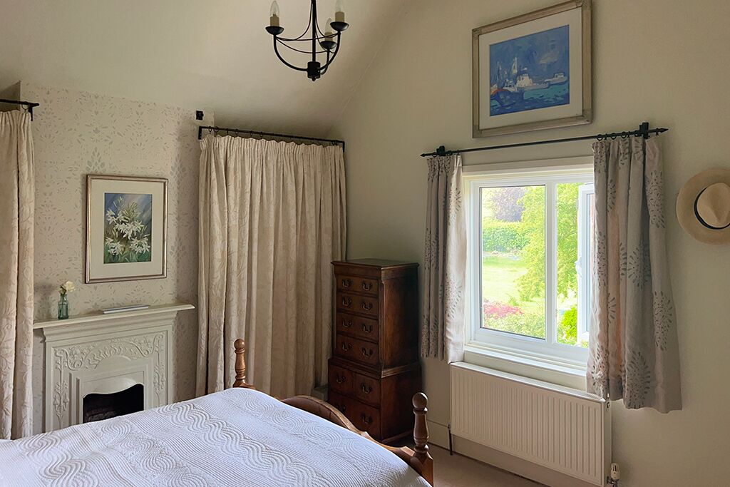 Bedroom with a bed, dresser, fireplace and curtained window