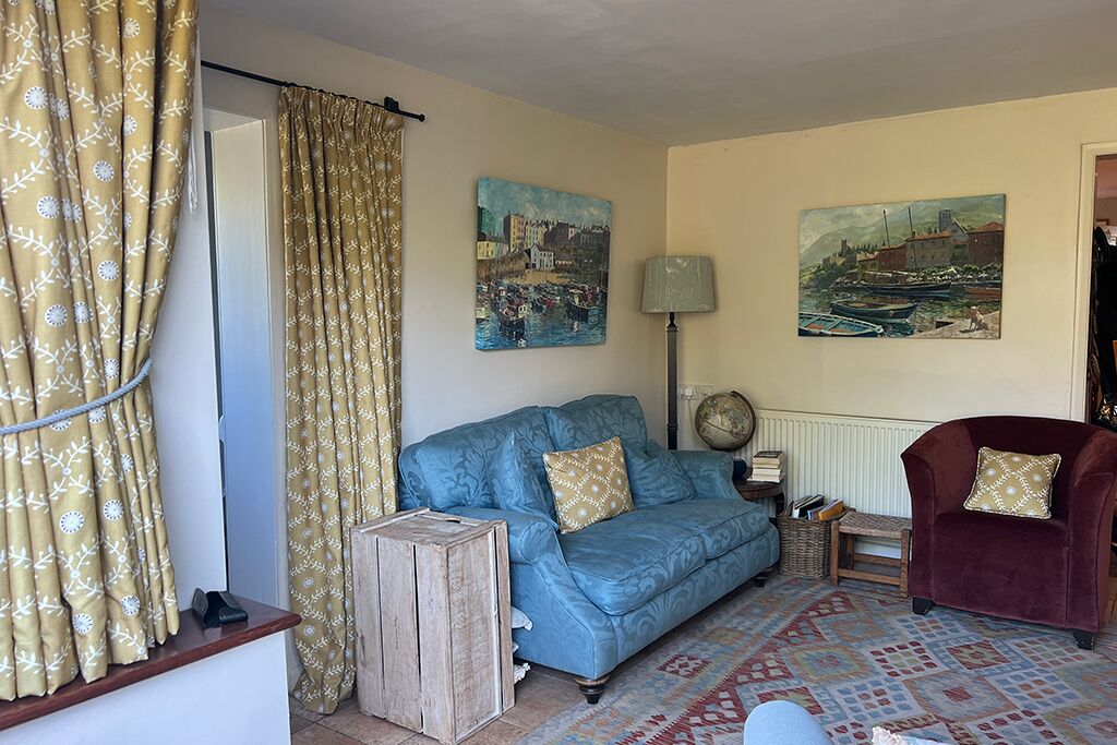 Living room with a blue sofa, red armchair, paintings and a lamp