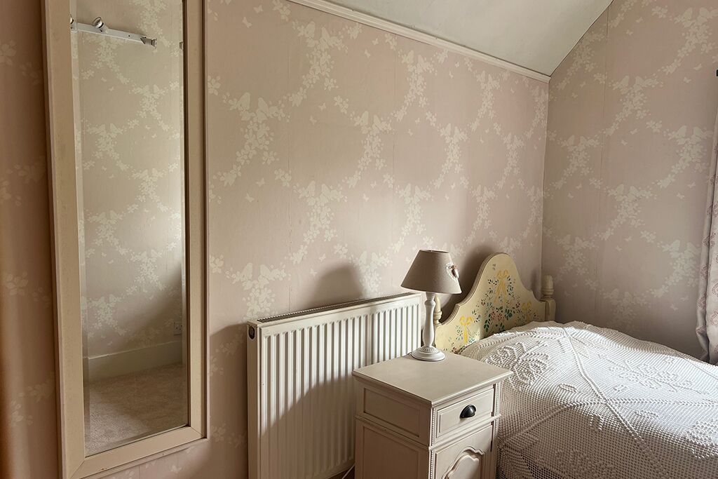 Bedroom with a bed, bedside table, lamp, dresser and mirror
